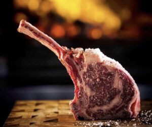 Tomahawk crudo de carne de la raza Black Angus sobre tabla de madera